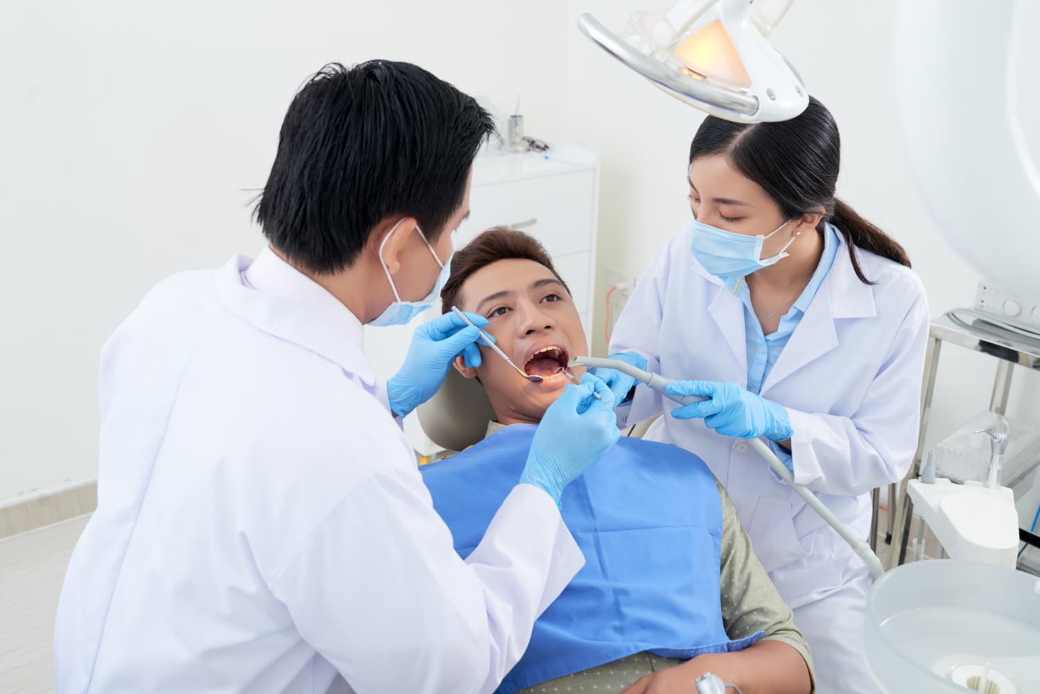 牙醫和牙科助手正在牙科診所對患者進行口腔檢查和牙周病治療。